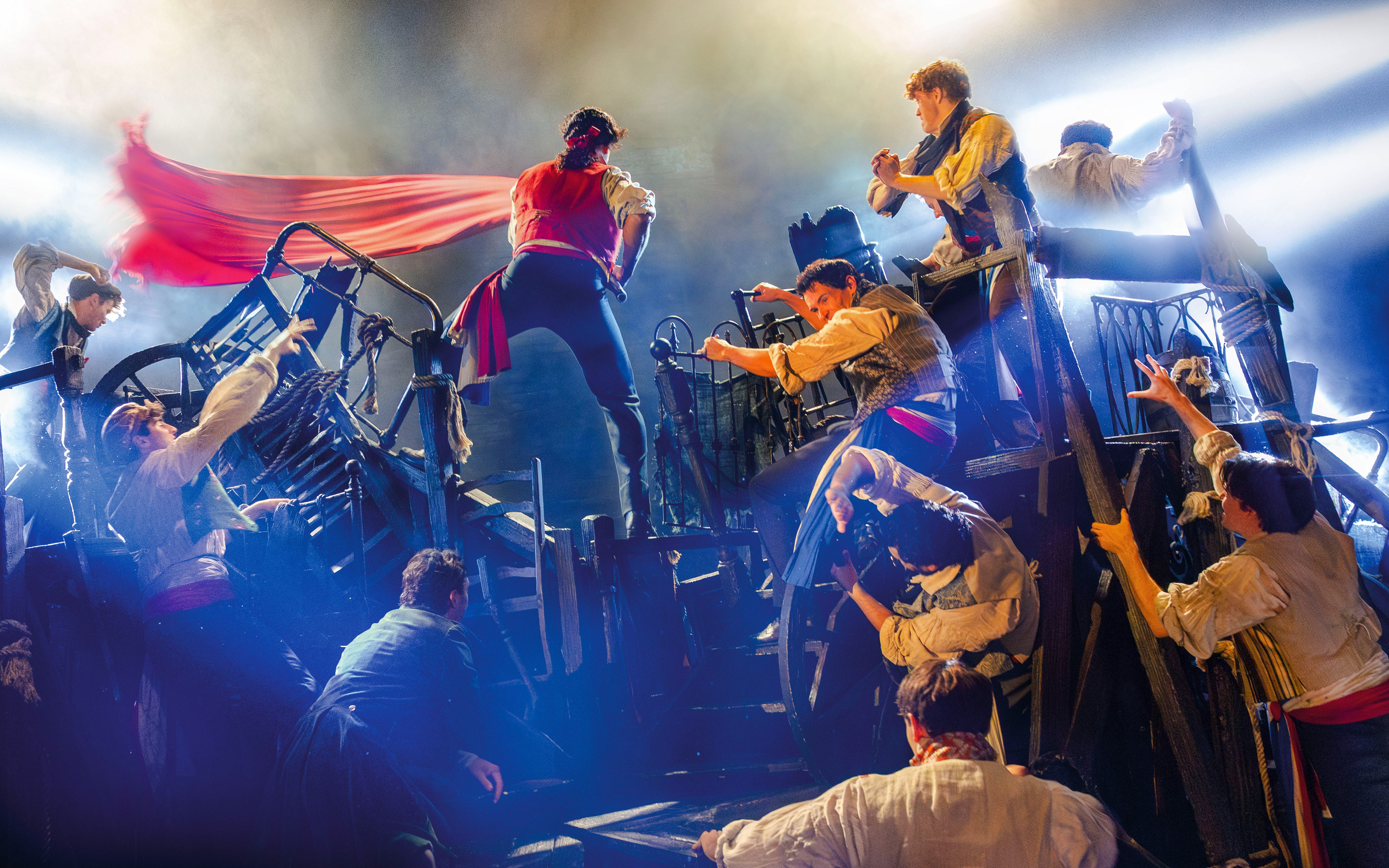 Actors perform a barricade scene from Les Misérables on stage.
