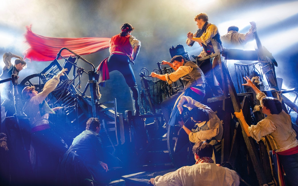 Actors perform a barricade scene from Les Misérables on stage.