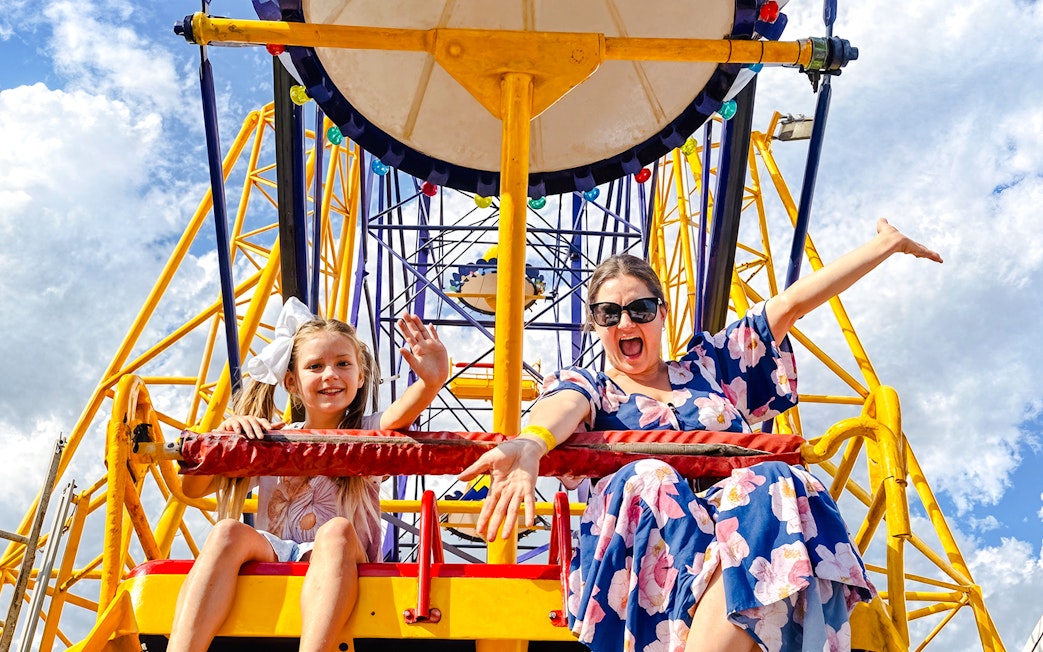 Mother and child on a Ferris wheel at Luna Park, smiling and waving.