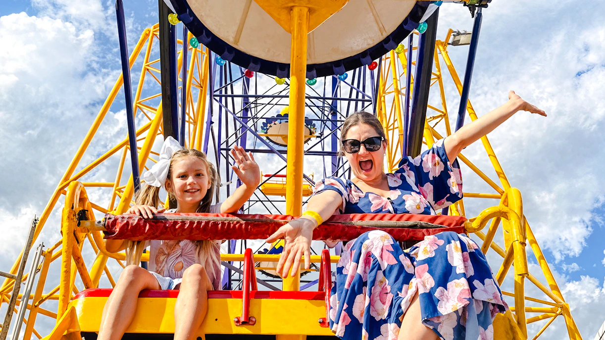 Mother and child on a Ferris wheel at Luna Park, smiling and waving.