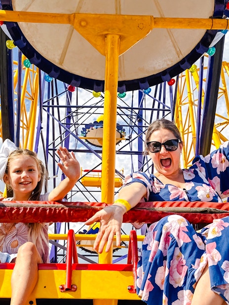 Mother and child on a Ferris wheel at Luna Park, smiling and waving.