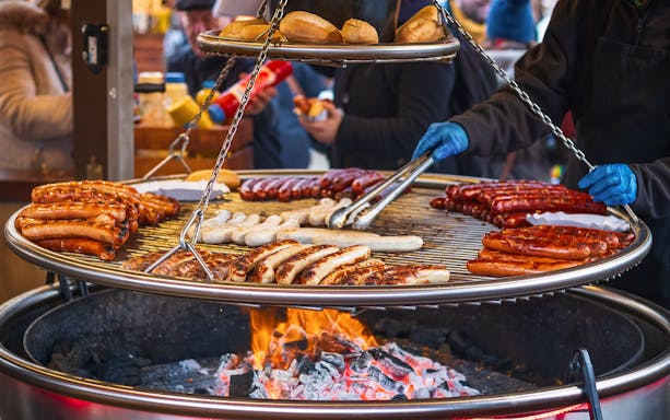 Sausages grilling over open flames at Christmas market in London.