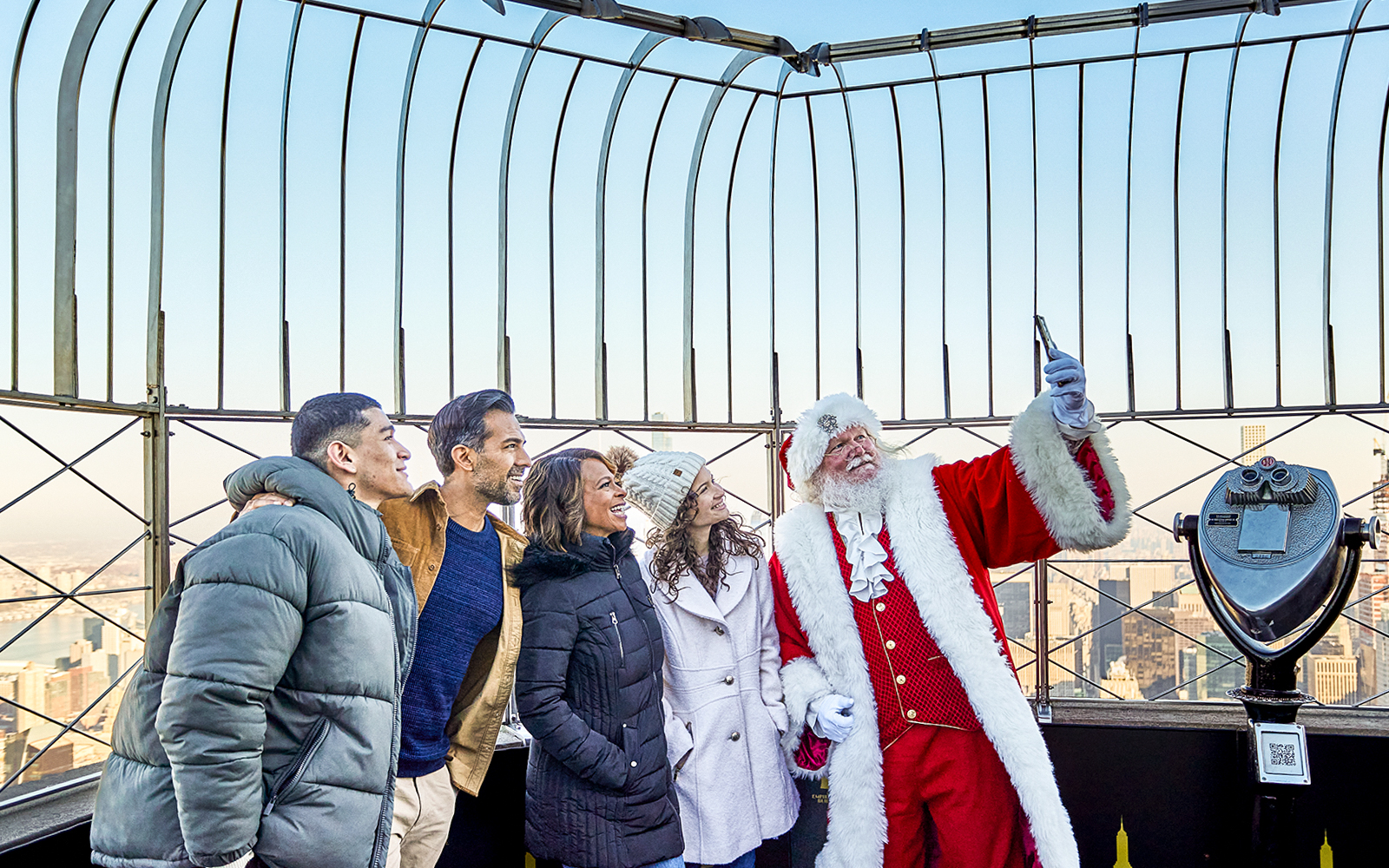 Santa taking selfies with visitors on the Empire State Building's observation deck.