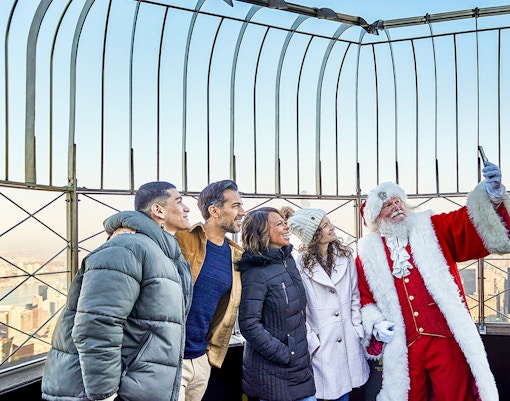 Santa taking selfies with visitors on the Empire State Building's observation deck.