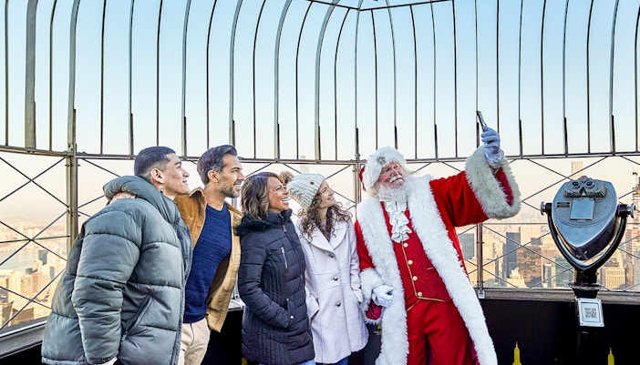 Santa taking selfies with visitors on the Empire State Building's observation deck.