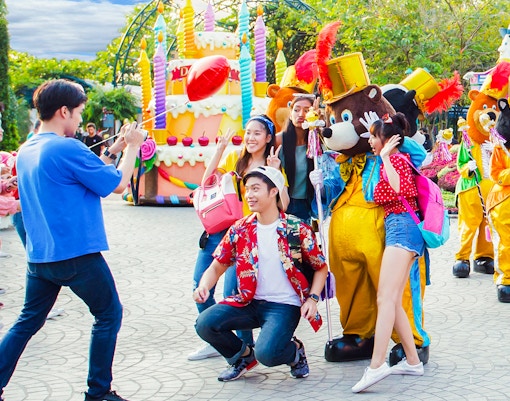 Visitors posing with costumed characters at Dreamworld Bangkok street show.