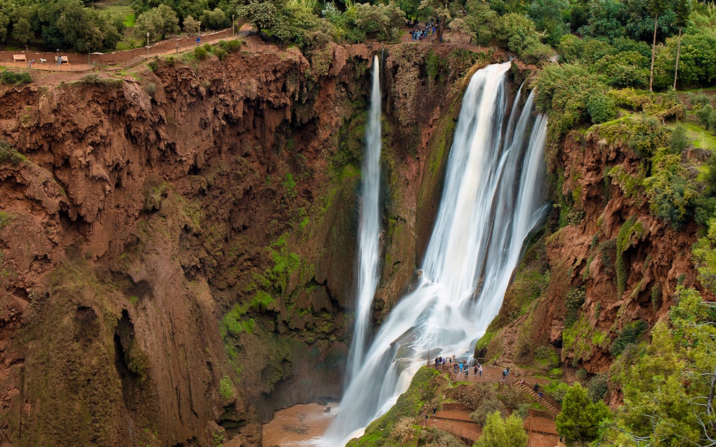 Ouzoud Waterfalls cascading in the Grand Atlas village of Tanaghmeilt, Morocco, with visitors on viewing platforms.