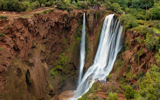 Ouzoud Waterfalls cascading in the Grand Atlas village of Tanaghmeilt, Morocco, with visitors on viewing platforms.