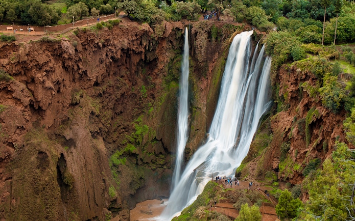 Ouzoud Waterfalls cascading in the Grand Atlas village of Tanaghmeilt, Morocco, with visitors on viewing platforms.