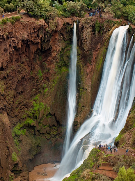 Ouzoud Waterfalls cascading in the Grand Atlas village of Tanaghmeilt, Morocco, with visitors on viewing platforms.