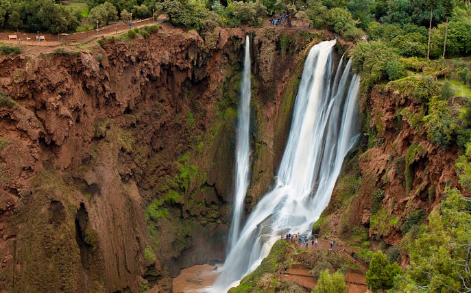Ouzoud Waterfalls cascading in the Grand Atlas village of Tanaghmeilt, Morocco, with visitors on viewing platforms.