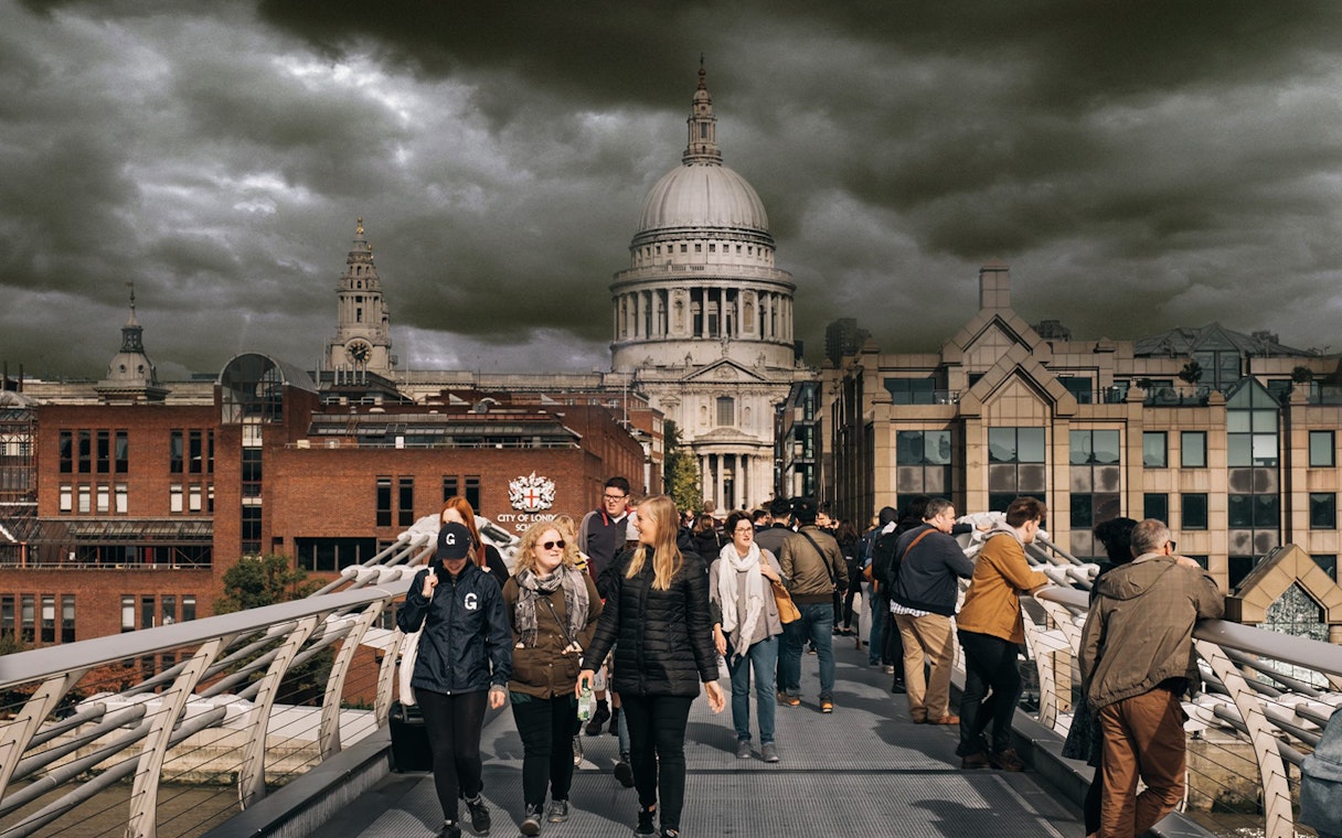 Visitors walking on Millennium Bridge with St. Paul's Cathedral in the background, London.