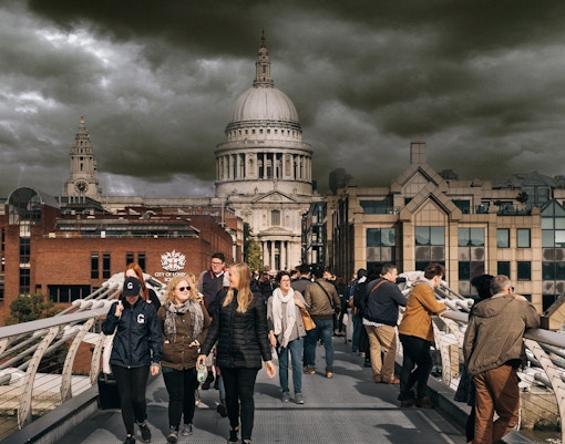 Visitors walking on Millennium Bridge with St. Paul's Cathedral in the background, London.