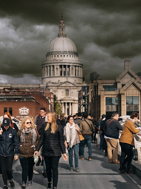 Visitors walking on Millennium Bridge with St. Paul's Cathedral in the background, London.