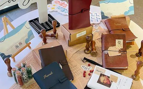 Handmade leather journals and crafting tools on a table in Hanoi workshop.