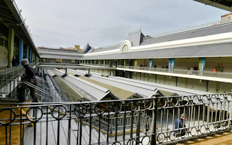 Bolhão Market interior with people walking along upper balcony in Porto, Portugal.