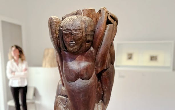 Wooden sculpture in Zadkine Museum, Paris, with a visitor in the background.