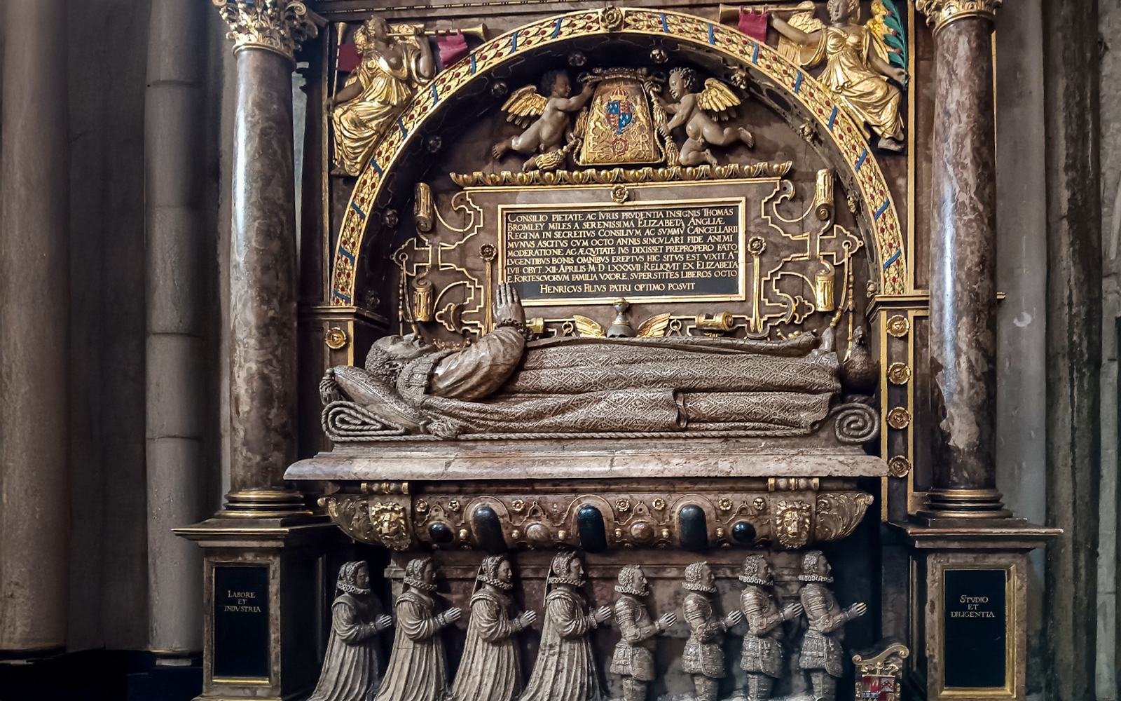 Tomb monument inside Westminster Abbey, featuring intricate carvings and Latin inscriptions.