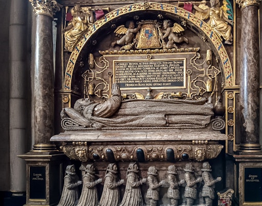 Tomb monument inside Westminster Abbey, featuring intricate carvings and Latin inscriptions.