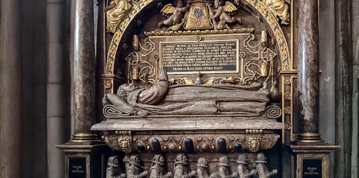 Tomb monument inside Westminster Abbey, featuring intricate carvings and Latin inscriptions.