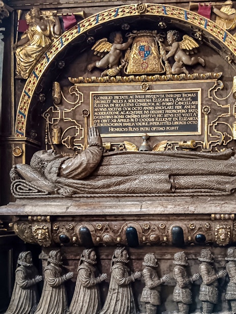 Tomb monument inside Westminster Abbey, featuring intricate carvings and Latin inscriptions.