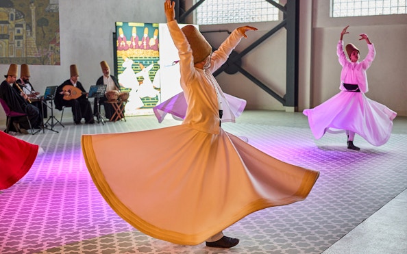 Whirling Dervishes performing traditional dance in Turkey with musicians in the background.