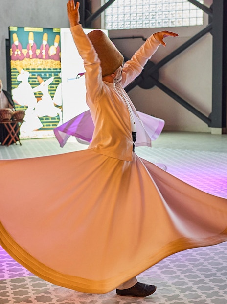 Whirling Dervishes performing traditional dance in Turkey with musicians in the background.