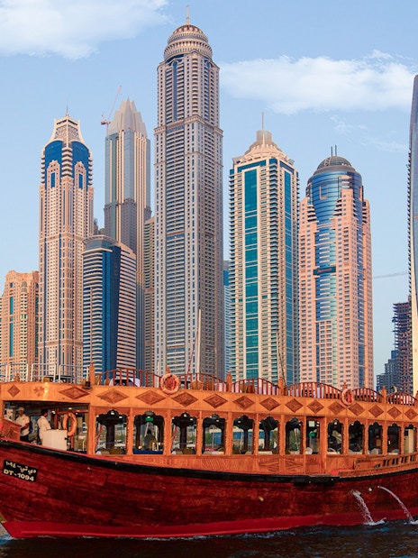 Dhow boat cruising in Dubai Marina with skyscrapers in the background.