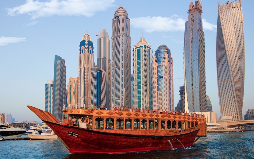 Dhow boat cruising in Dubai Marina with skyscrapers in the background.