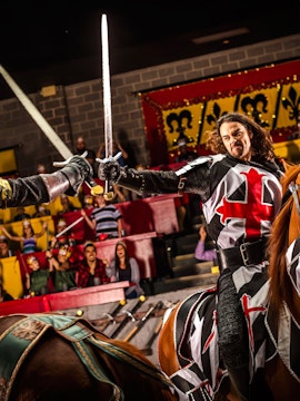 Knight in armor on horseback wielding sword during Medieval Times Dinner and Show.