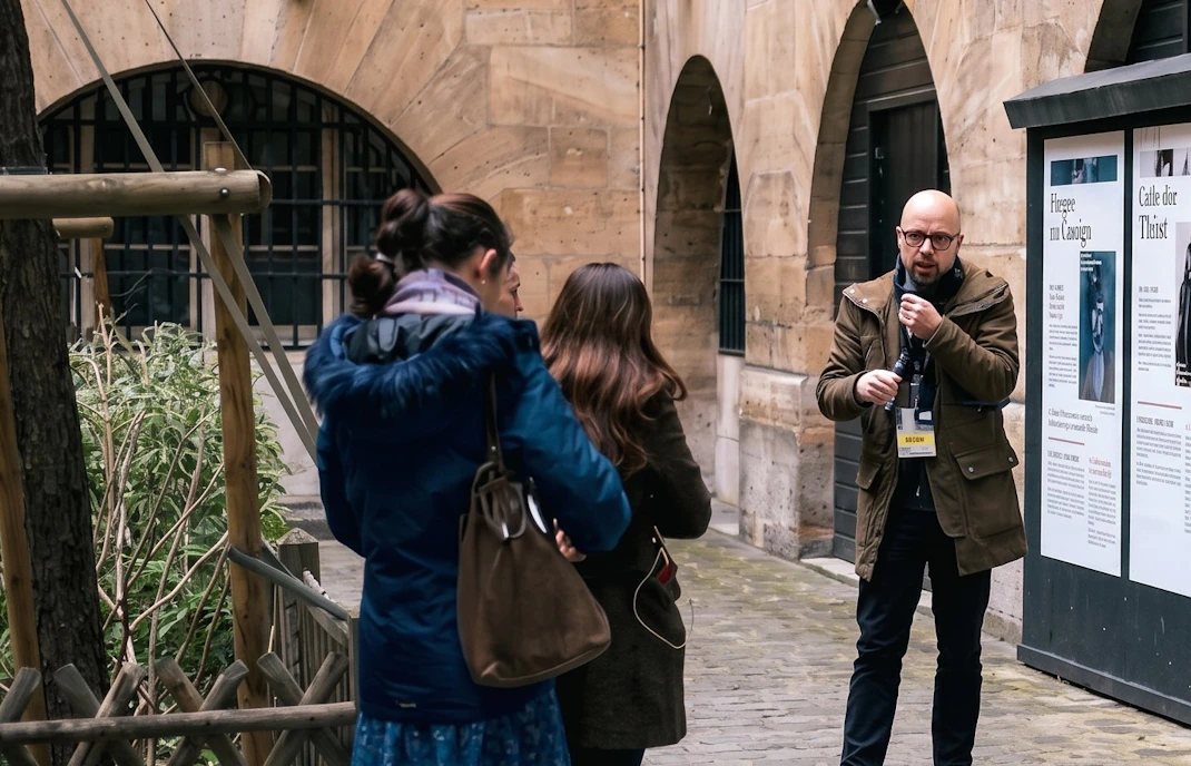 Tour guide explaining history to visitors at Sainte Chapelle and Conciergerie in Paris.