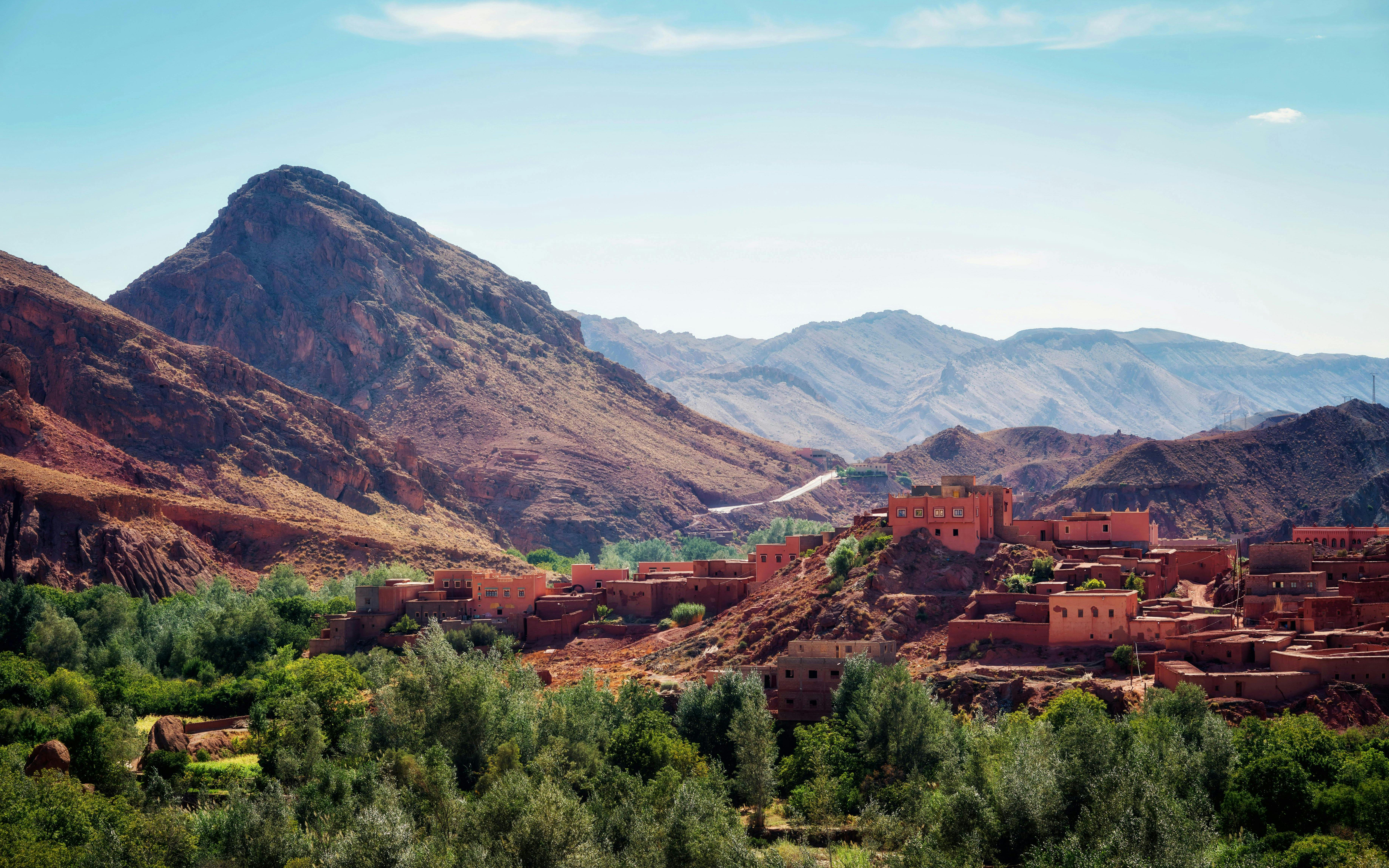 Traditional Berber village in the Atlas Mountains, Morocco, with rugged peaks in the background.