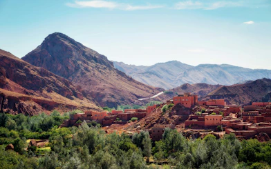 Traditional Berber village in the Atlas Mountains, Morocco, with rugged peaks in the background.