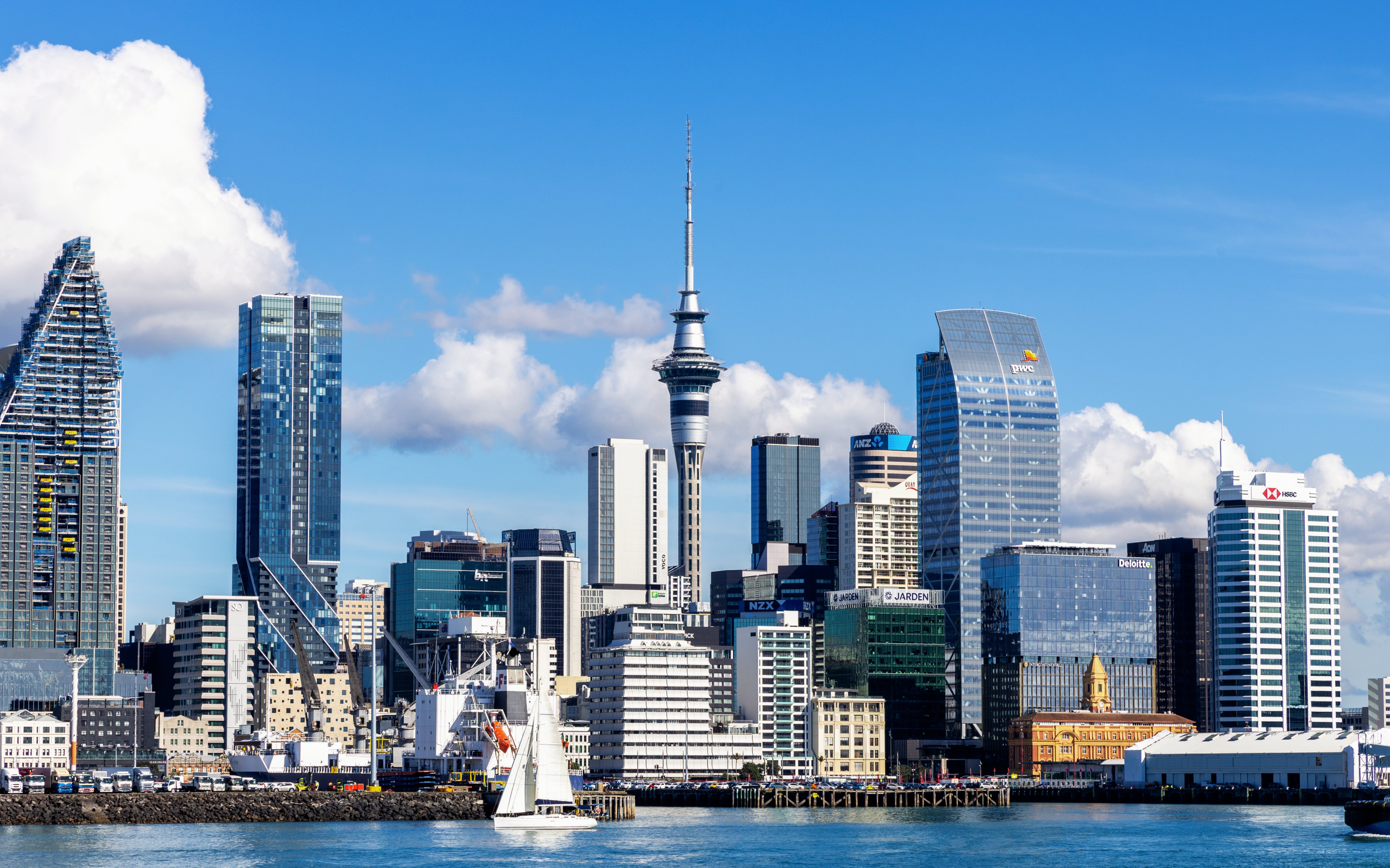 Auckland skyline featuring the Sky Tower with sailboat in foreground.
