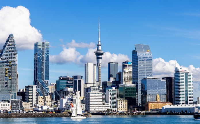 Auckland skyline featuring the Sky Tower with sailboat in foreground.