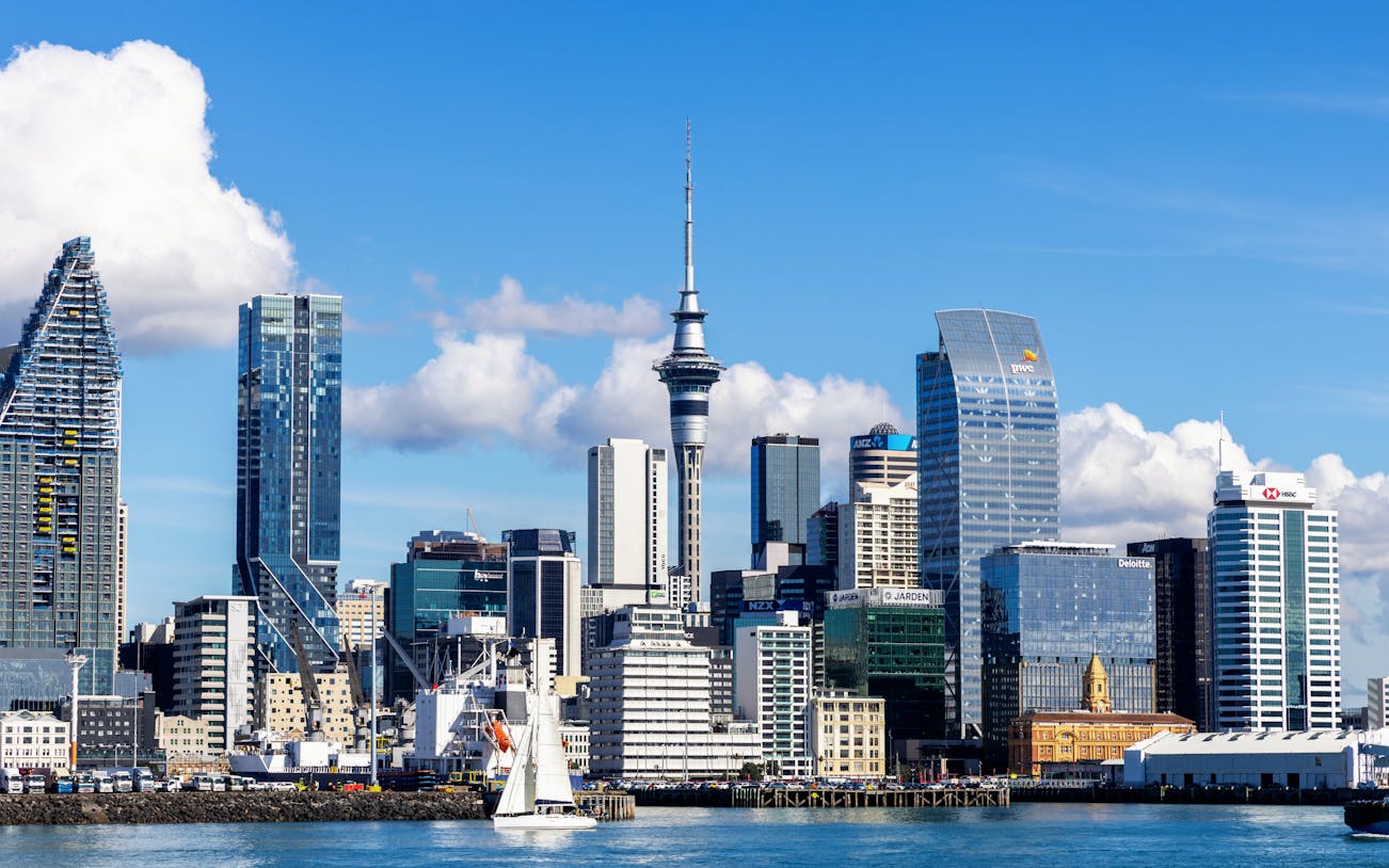 Auckland skyline featuring the Sky Tower with sailboat in foreground.