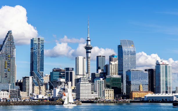 Auckland skyline featuring the Sky Tower with sailboat in foreground.