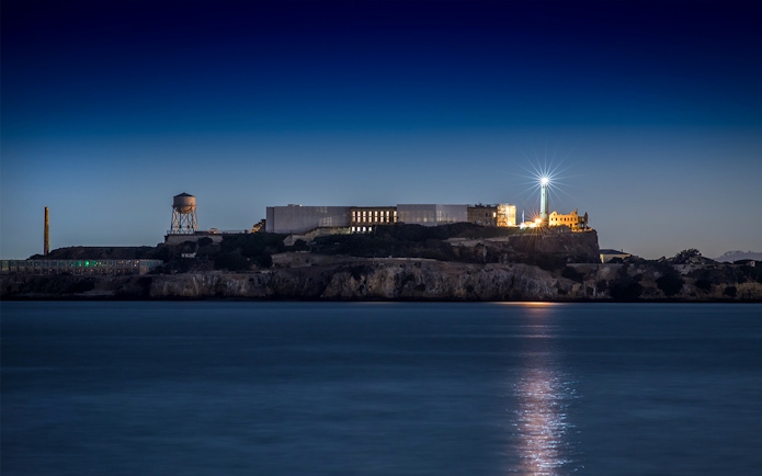 Alcatraz Island with lighthouse illuminated at night, San Francisco Bay.