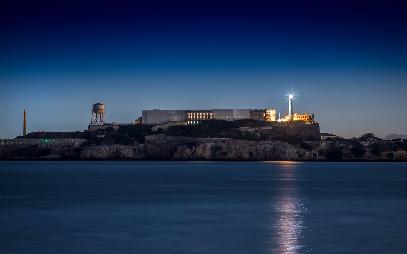 Alcatraz Island with lighthouse illuminated at night, San Francisco Bay.