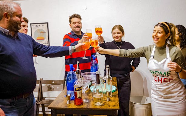 Participants toasting with Aperol Spritz at a cooking class in Rome.