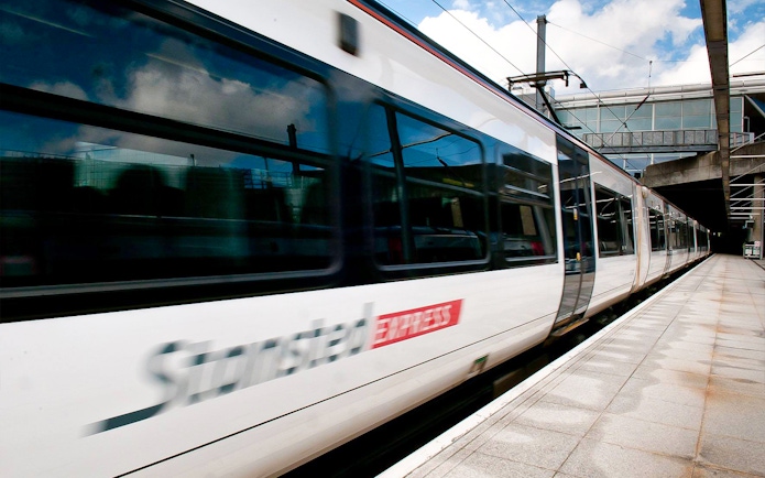 Stansted Express train arriving at a modern train station platform.