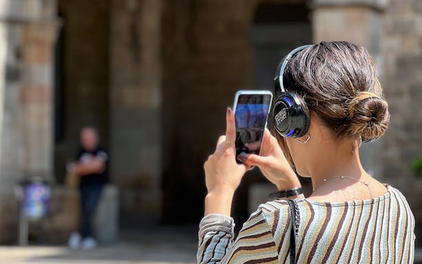 Tourist in Barcelona using headphones and phone during guided tour.
