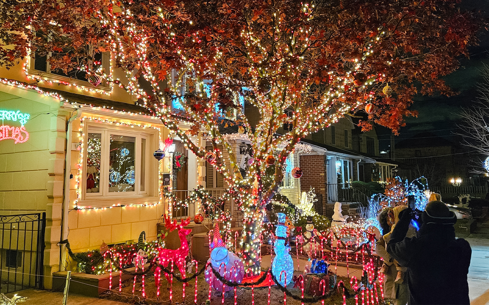 Christmas lights display on a New York house with festive decorations and visitors taking photos.
