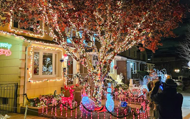 Christmas lights display on a New York house with festive decorations and visitors taking photos.
