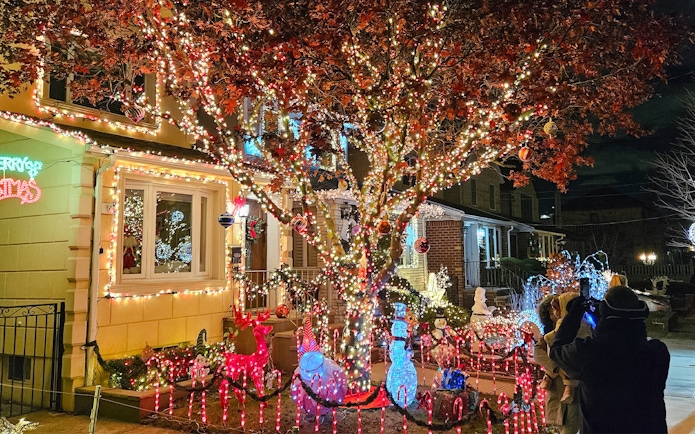Christmas lights display on a New York house with festive decorations and visitors taking photos.
