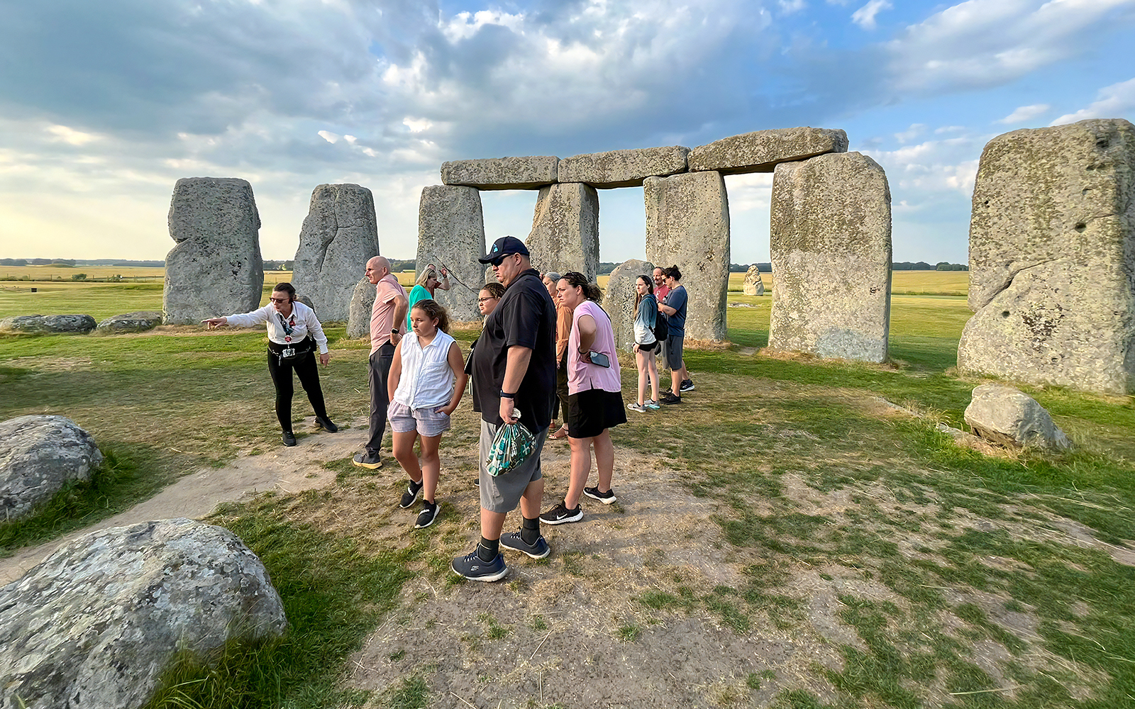 Family exploring Stonehenge with a guide in Wiltshire, England.