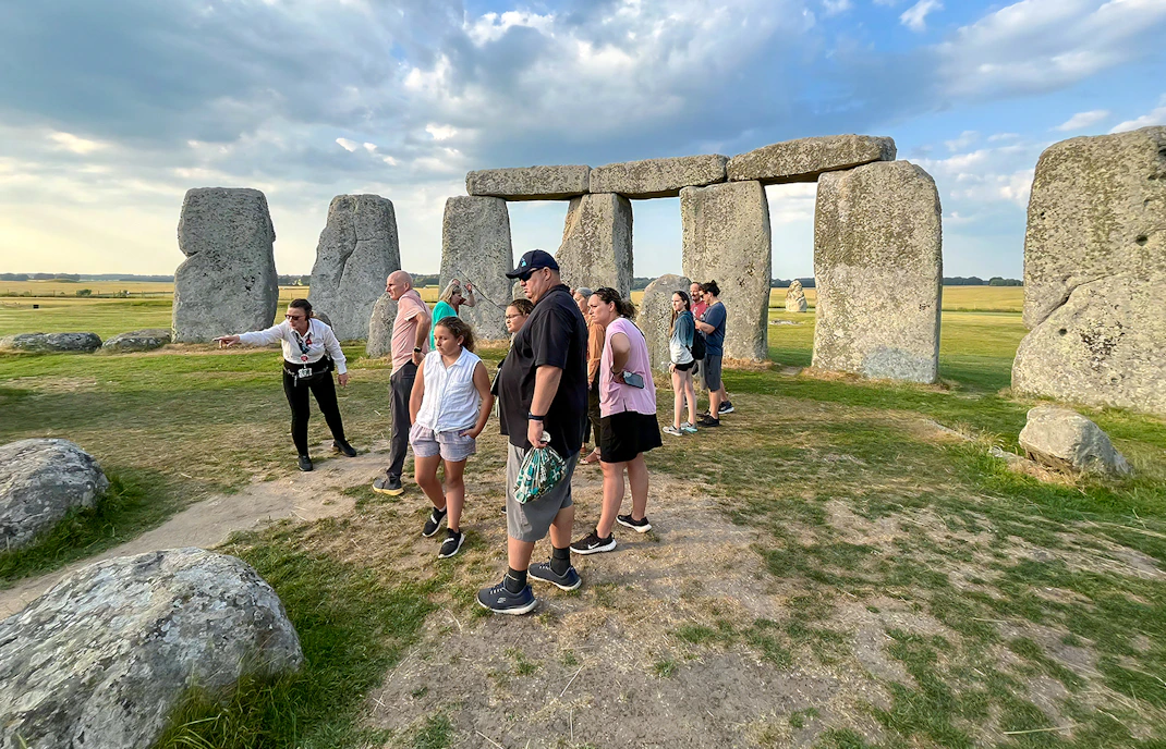 Family exploring Stonehenge with a guide in Wiltshire, England.