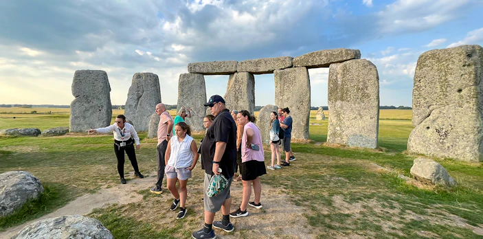Family exploring Stonehenge with a guide in Wiltshire, England.