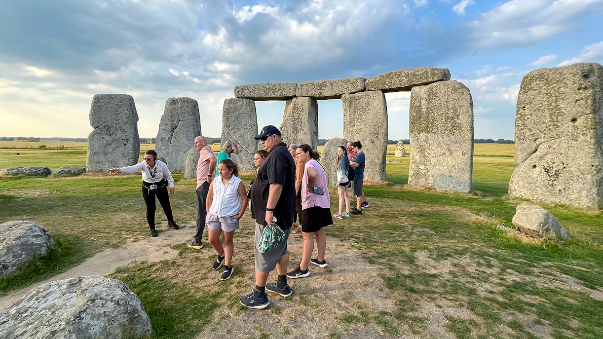 Family exploring Stonehenge with a guide in Wiltshire, England.
