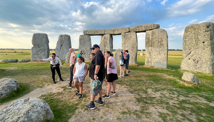 Family exploring Stonehenge with a guide in Wiltshire, England.